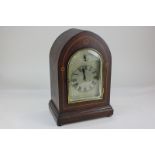 An Edwardian inlaid mahogany chiming mantel clock with silvered dial in arch shaped case, with