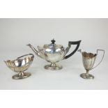 An Edward VII silver three-piece tea set of teapot, sugar basket and cream jug, oval shape on