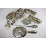 A late Victorian silver seven piece dressing table set of four brushes, hand mirror, trinket dish