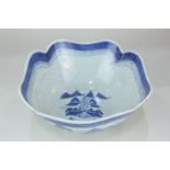 A Chinese blue and white bowl, shaped border, decorated with river views and buildings, on