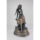 A bronzed spelter figure of a lady combing her hair, seated on a rock beside two swans, mounted on