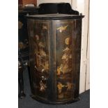 A chinoiserie black lacquered bow front corner wall cupboard with red painted interior of three