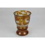 A Bohemian amber glass beaker cut to opaque glass depicting a stag and doe running through wooded