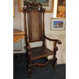 A Carolean style carved oak armchair with serpent carved surmount, cane panel back and seat, with