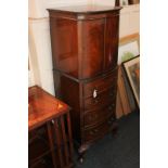A mahogany reproduction small tallboy cabinet with twin oval panelled door above four drawers, on