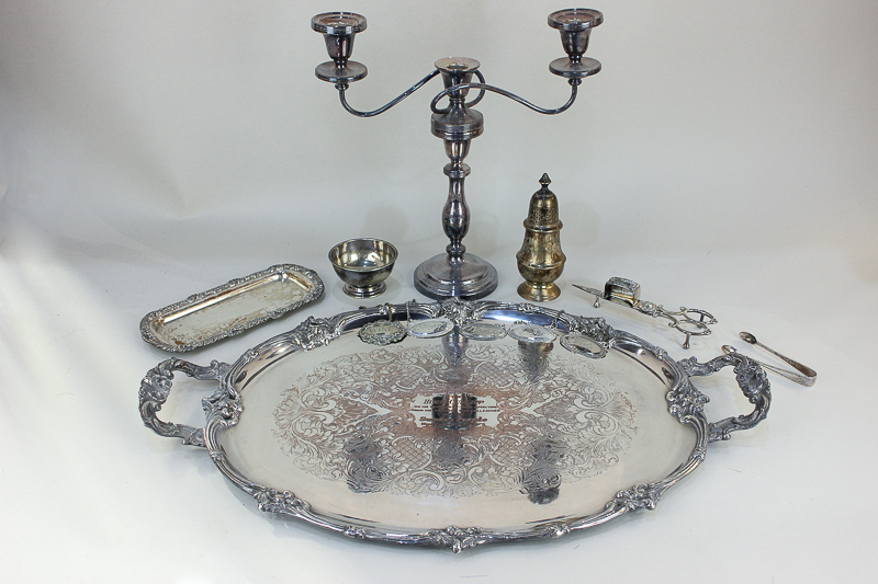 A large silver plated oval tea tray with two scroll handles, a three-sconce candelabra, a candle