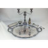 A large silver plated oval tea tray with two scroll handles, a three-sconce candelabra, a candle