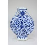 A Chinese pottery blue and white moon flask with dragon lugs and all-over floral design, 26cm high