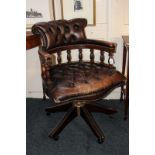 A brown leather button upholstered office chair, on swivel base and castors