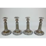 A set of four Sheffield silver plated candlesticks with foliate cast urn sconces, on fluted