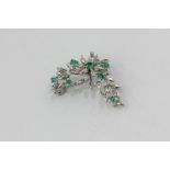 An emerald and diamond brooch, flower head and leaf design, set with eight cut diamonds and