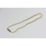 A single row graduated pearl necklace on a sapphire and white gold clasp