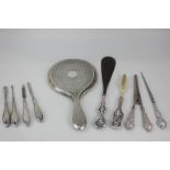 A George V silver mounted hand mirror, a set of four silver mounted manicure tools, a silver mounted