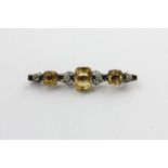A citrine bar brooch claw set with graduated stones with white pastes between