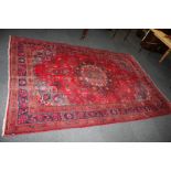 A Turkish wool rug with central design within multi-line borders, various hues on red ground,