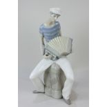 A Lladro Figure of an Accordion Player seated on a bale, designed by Salvador Furio (1970-1981),