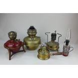 A collection of five various oil lamps and burners, including three brass, and one painted red metal