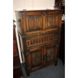 A carved oak drinks cabinet with metamorphic pull-out top revealing mirror lined interior with glass