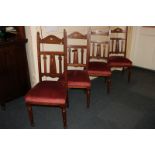 Four Arts and Crafts mahogany dining chairs with pierced back splats over upholstered seats, on