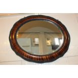 An oval wall mirror with simulated rosewood wooden frame, 67cm