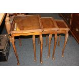 A nest of three carved wood side tables with shaped rectangular top and glass insert, on slender