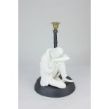 A black candle holder mounted with white seated figure of a woman, one knee raised in a