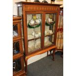 An Art Nouveau inlaid mahogany display cabinet with two shelves enclosed by two lead glazed panel