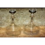 A graduated pair of plain glass spirit decanters, (LC)