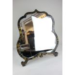An early 20th century chinoiserie lacquered dressing table mirror, cartouche shape, on scroll
