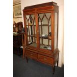 An Edwardian inlaid mahogany display cabinet with arch panelled glazed doors enclosing shelves, with