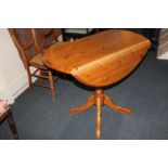 A modern pine circular pedestal table with two drop flaps, turned stem on four outswept legs, 92cm