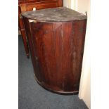 An early 19th century mahogany bow front hanging corner wall cupboard with single door enclosing