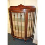 A mahogany demi-lune display cabinet with two glass shelves enclosed by panel glazed door, on