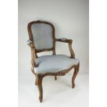 A Victorian style child's armchair with exposed carved wood frame, upholstered back, seat and