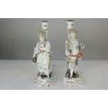 A pair of Sitzendorf porcelain figure candlesticks and a gentleman and lady carrying a basket of
