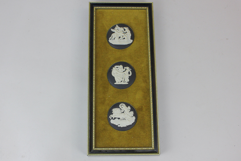 Three Wedgwood Jasperware circular plaques depicting classical scenes, on black ground, mounted in