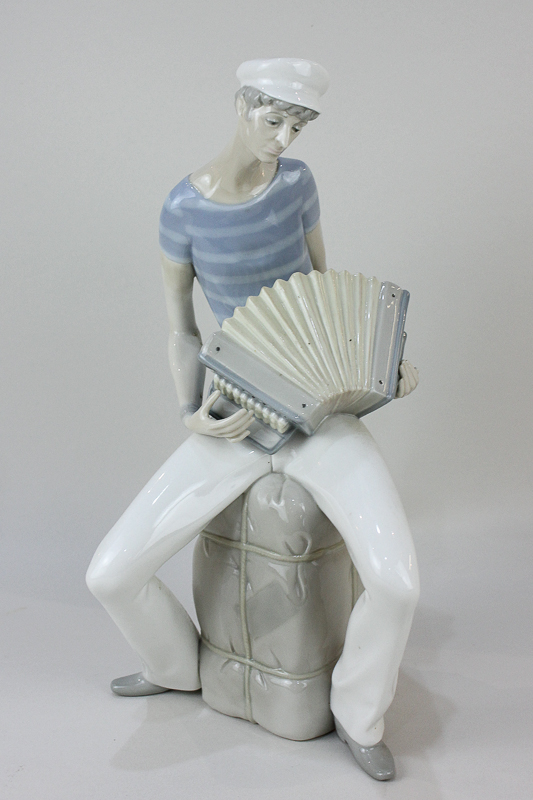 A Lladro Figure of an Accordion Player seated on a bale, designed by Salvador Furio (1970-1981),