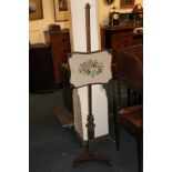 A mahogany adjustable fire screen with floral woolwork panel, on baluster carved stem and raised