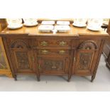 20th cent. Oak heavily carved side board, 2 central drawers over a single door cupboard, flanked