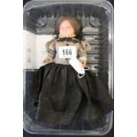 19th cent. Doll: Celluloid doll with dark hair, black lace cap, leg-o-mutton sleeve, brown check