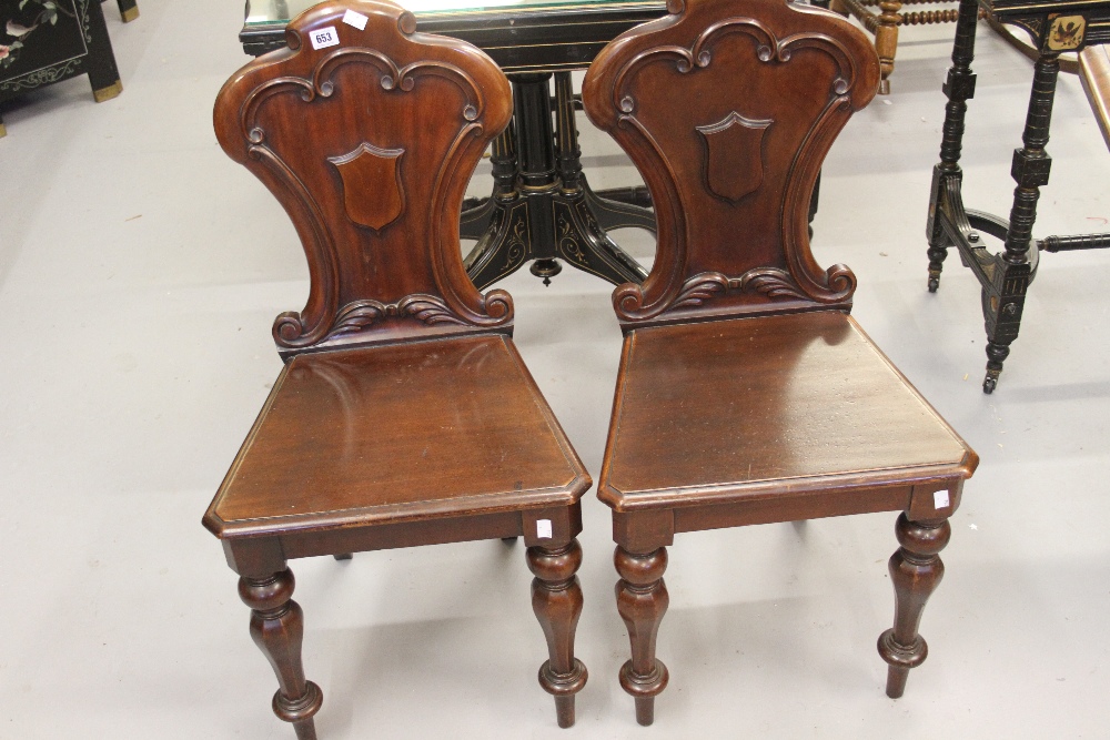 Early Victorian hall chairs, c1850, the scroll carved spoon shaped backs applied with shields