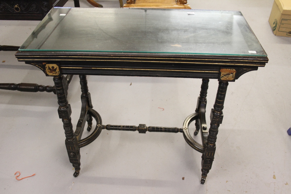 Late Victorian ebonised card table, circa 1885, the hinged rectangular top with a canted edge