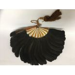 A FRENCH PHEASANT FEATHER FAN, WITH AMBER COLOURED PLASTIC SPINES AND A SILK TASSLE.
