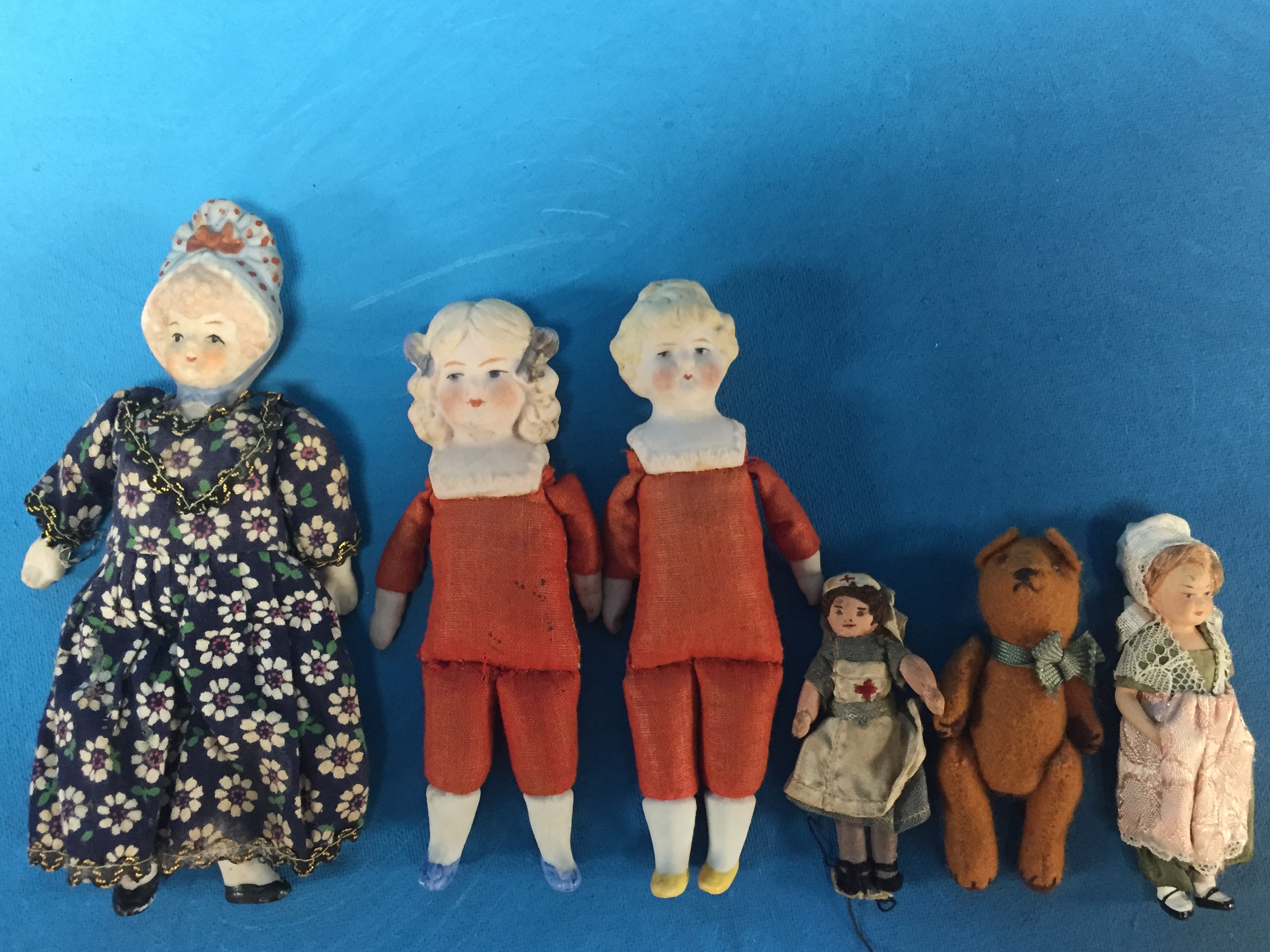 FOUR VICTORIAN MINIATURE PORCELAIN HEADED DOLLS AND A SMALL TEDDY AND MINIATURE CLOTH NURSE DOLL