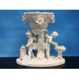 C19TH ENGLISH GEORGE MOORE FIGURE OF CHERUB BLACKSMITHS HOLDING A BOWL ON TREESTUMP OVER FLOWERS.