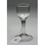 An 18th century plain stemmed wine glass, with small cup shaped bowl over a broad spreading