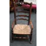 An early 19th century Lancashire ladder back nursing armchair, with rush seat over turned supports