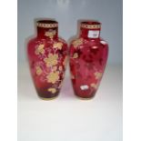 A pair of Edwardian cranberry florally enamel decorated glass vases