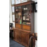 An early 19th century mahogany cupboard bookcase, the moulded cornice over a pair of glazed and