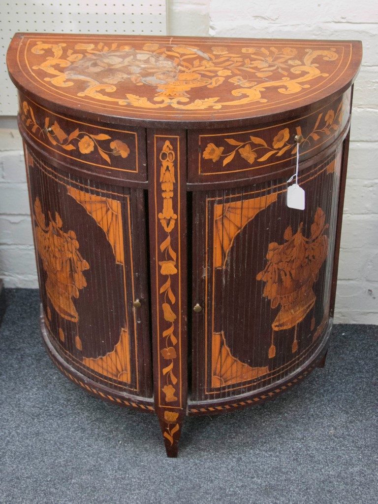 An early 19th century Dutch marquetry demi-lune cupboard, the top decorated with a flowering urn